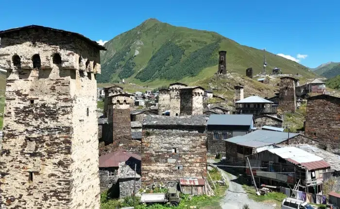 Tours défensives médiévales d’Ushguli, Svanétie (Géorgie), au pied des montagnes verdoyantes sous ciel bleu.