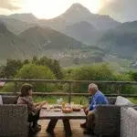 Couple savourant un dîner en terrasse face au mont Kazbek et à l'église de Guerguéti en Géorgie.